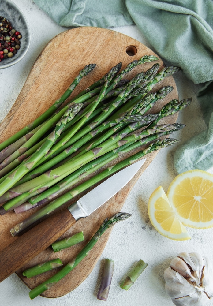 Fresh,Green,Asparagus,Lies,On,A,Wooden,Cutting,Board,Alongside